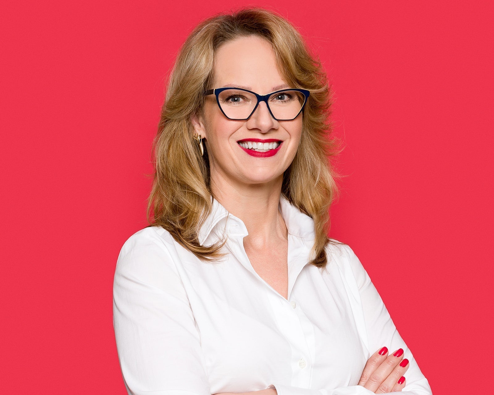 Finished corporate headshot of a professional in a white shirt and dark glasses on a red backdrop