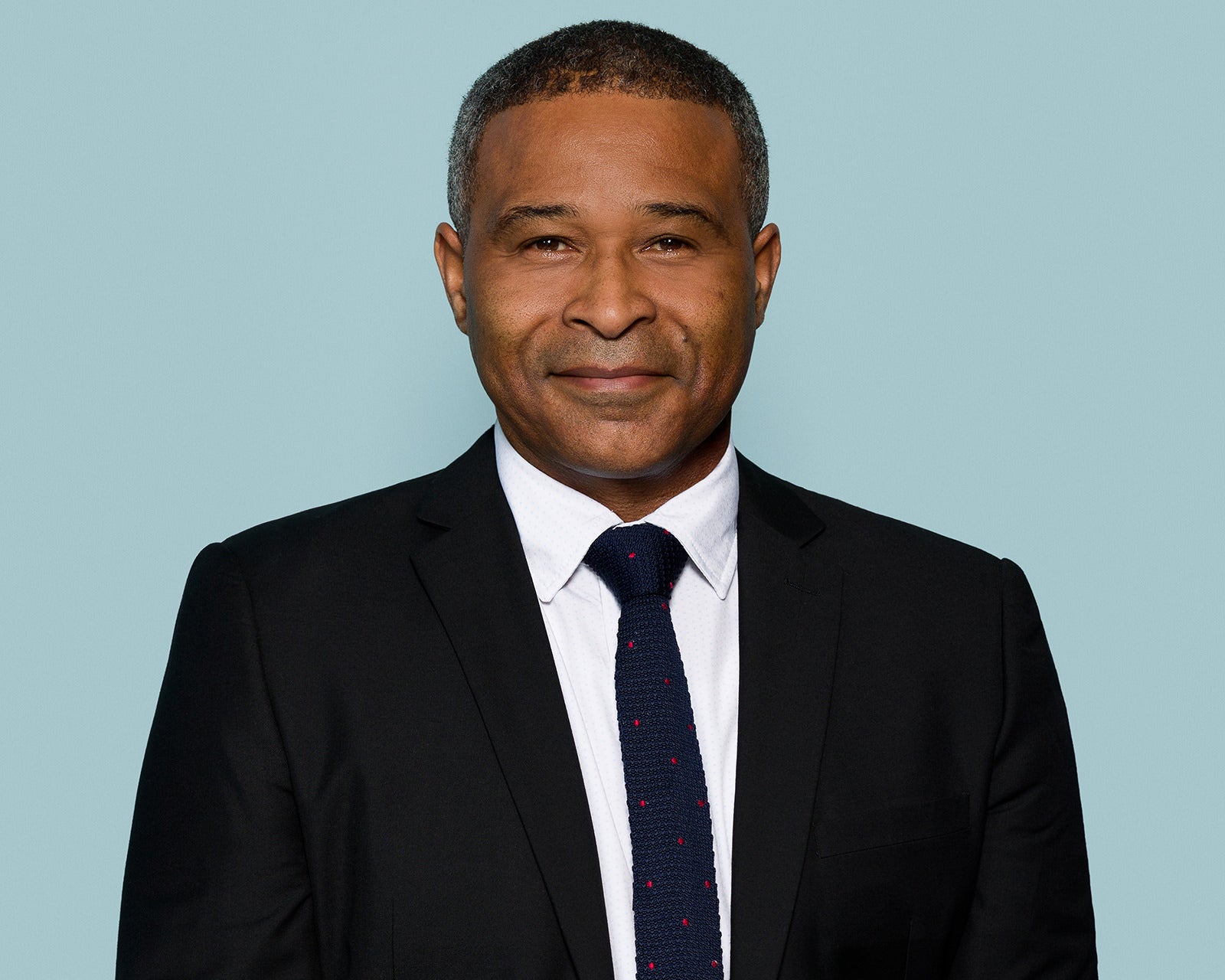 Corporate headshot of a mid-career professional against a soft blue background