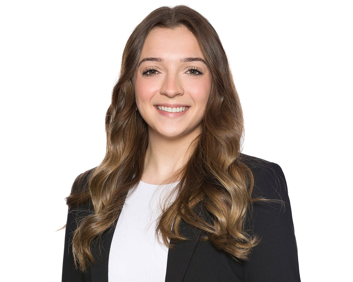 Professional corporate headshot of a woman in a black blazer on a white backdrop from a company headshot day