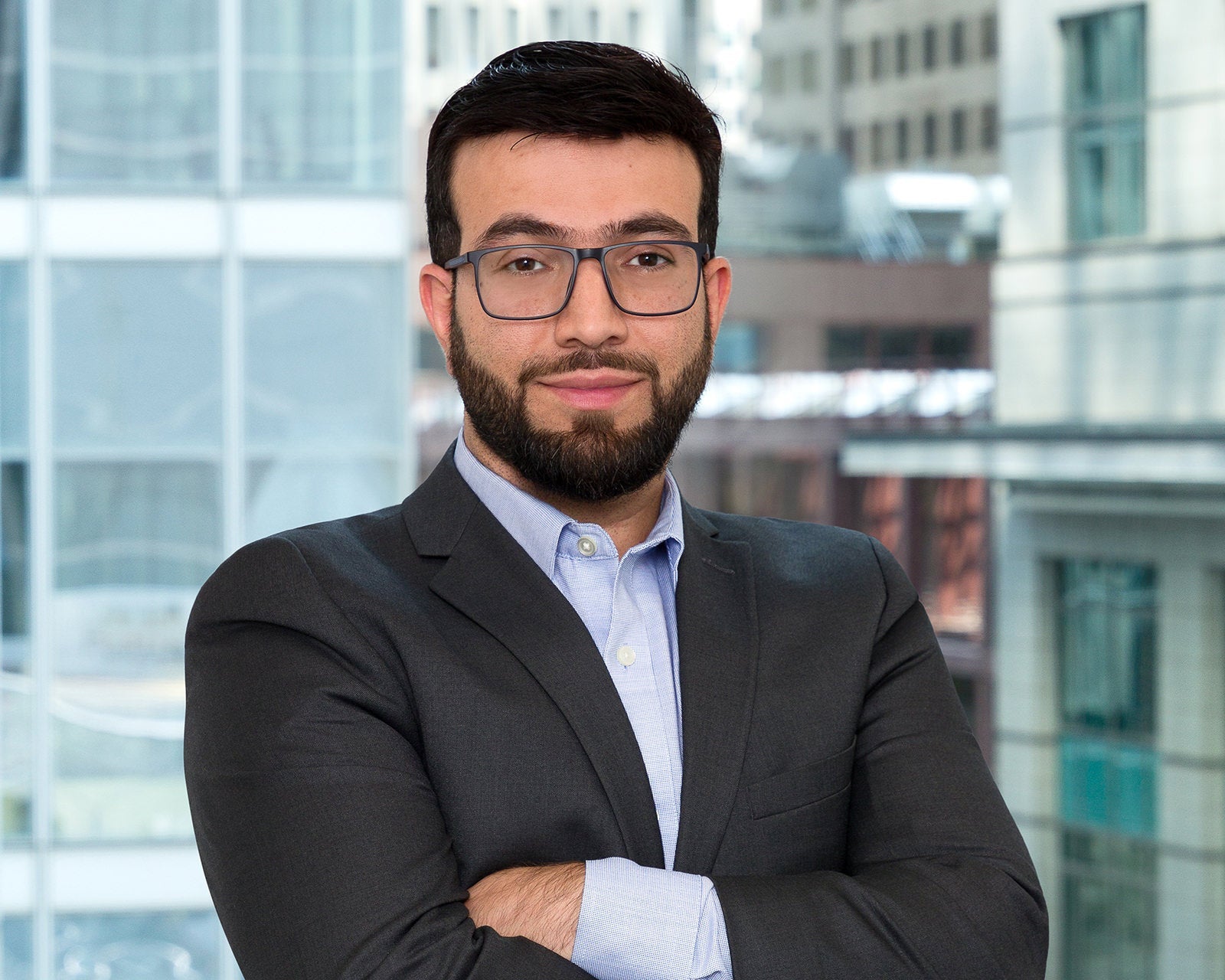 Corporate headshot of a professional photographed in an office boardroom with the workspace view behind them.