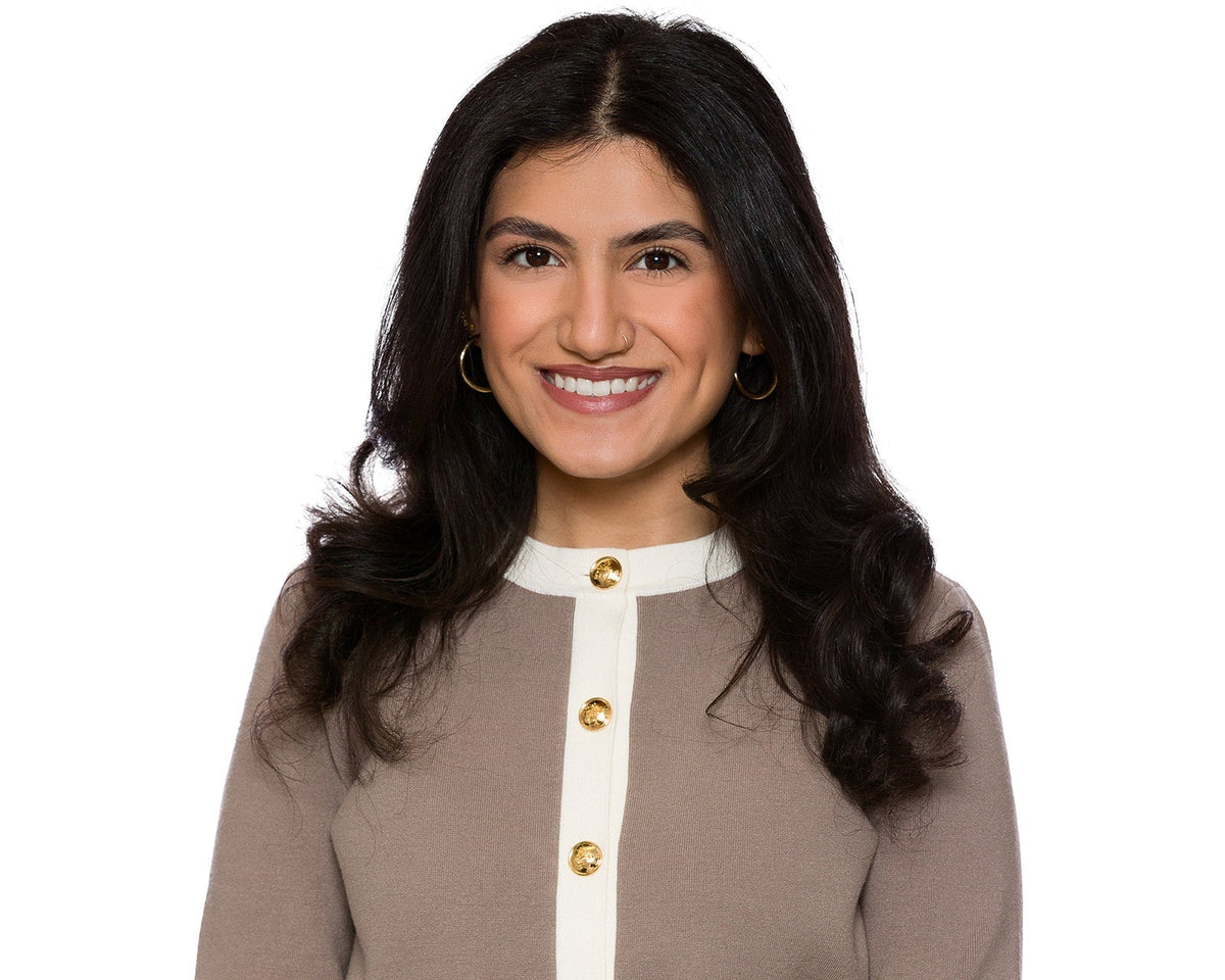 Real estate headshot of a woman in a taupe cardigan with cream trim and gold buttons on a white background