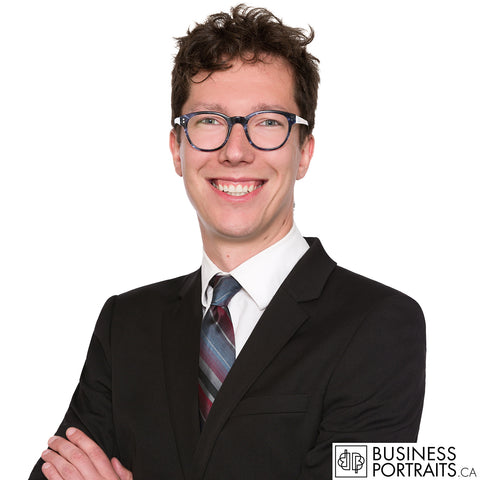 Lawyer headshot of a young associate with curly hair and glasses in a black suit, white background