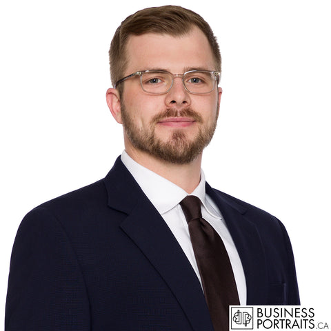 Law firm headshot of a bearded lawyer in glasses and a navy suit, matched to the firm standard