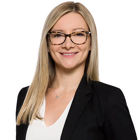 Law firm headshot of a blonde woman lawyer in glasses and a black blazer, white background
