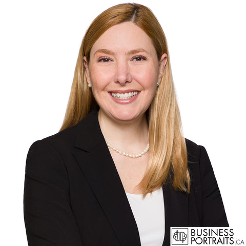 Lawyer headshot of a woman with long auburn hair in a black blazer and pearls, white background